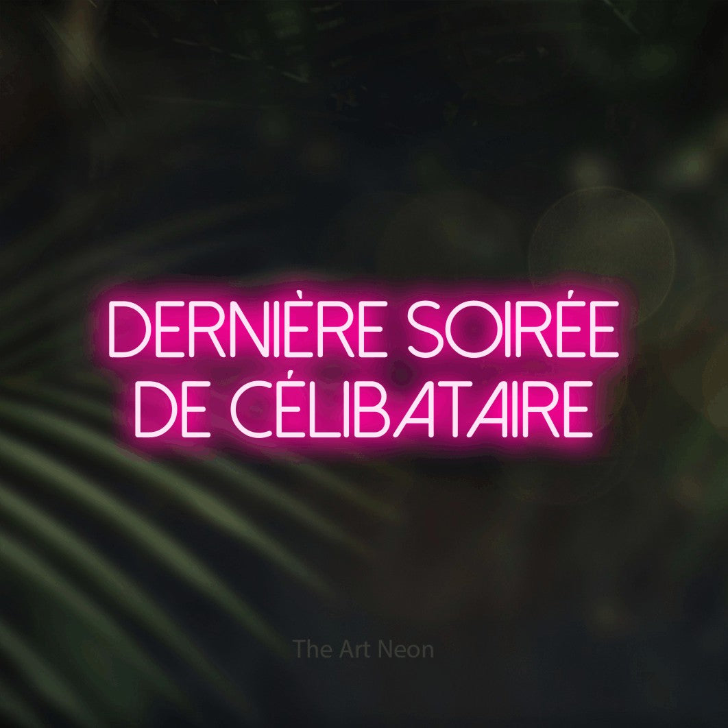 “Dernière soirée de célibataire” LED neon sign in hot pink, with thin sans-serif lettering across 2 lines, shown against a blurred palm and bokeh-light backdrop.