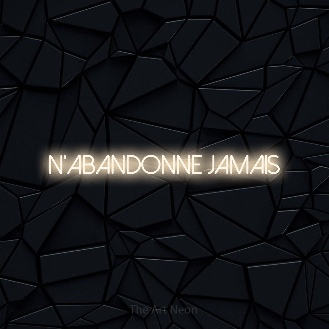 “N'abandonne jamais” LED neon sign in warm white, with thin sans-serif lettering, shown against a black polygonal surface.