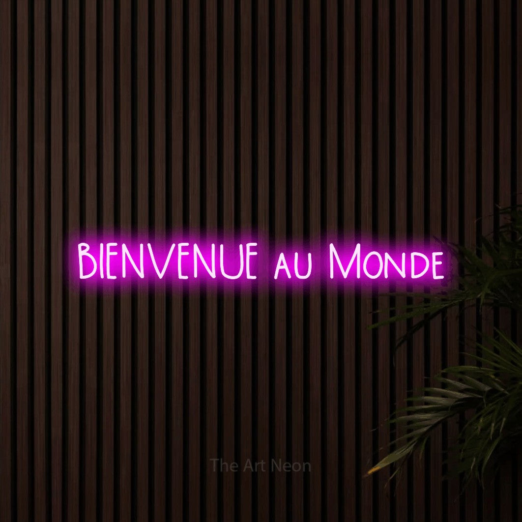 “Bienvenue au monde” LED neon sign in pink, with narrow hand-drawn lettering, shown against dark wooden wall slats.