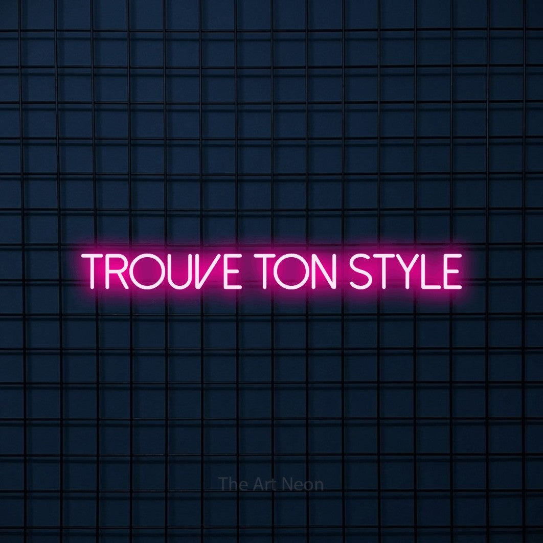 “Trouve ton style” LED neon sign in hot pink, with thin sans-serif lettering, shown against a dark blue grid.