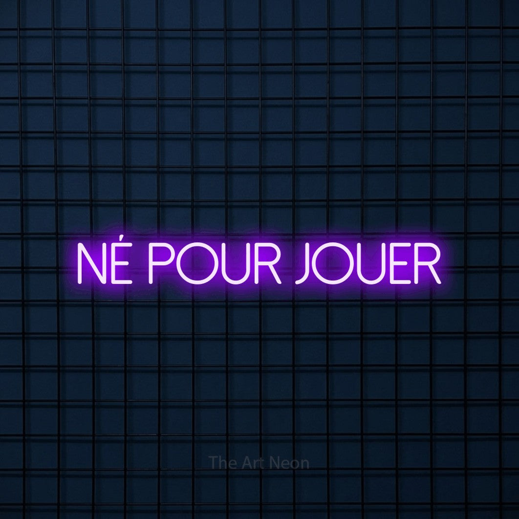 “Né pour jouer” LED neon sign in purple, with thin sans-serif lettering, shown against a dark blue grid.