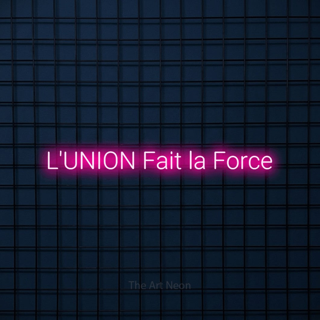 “L'union fait la force” LED neon sign in hot pink, with rounded sans-serif lettering, shown against a dark blue grid.