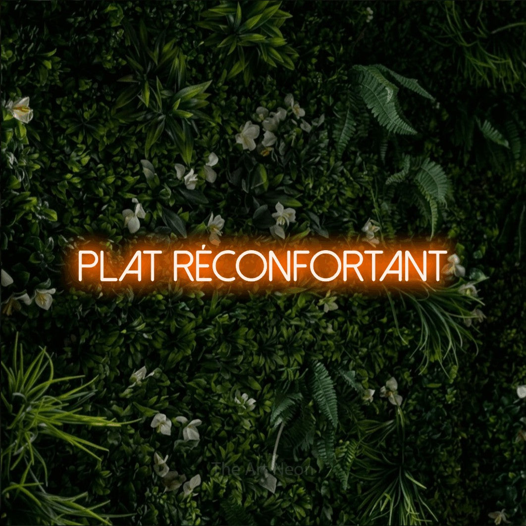 “Plat réconfortant” LED neon sign in orange, with thin sans-serif lettering, shown against a dense green plant wall.