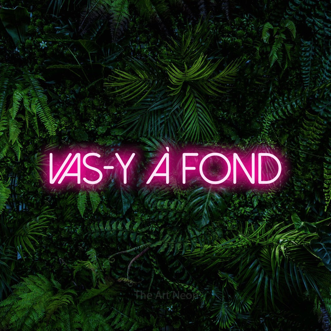 “Vas-y à fond” LED neon sign in hot pink, with thin sans-serif lettering, shown against dense tropical foliage.