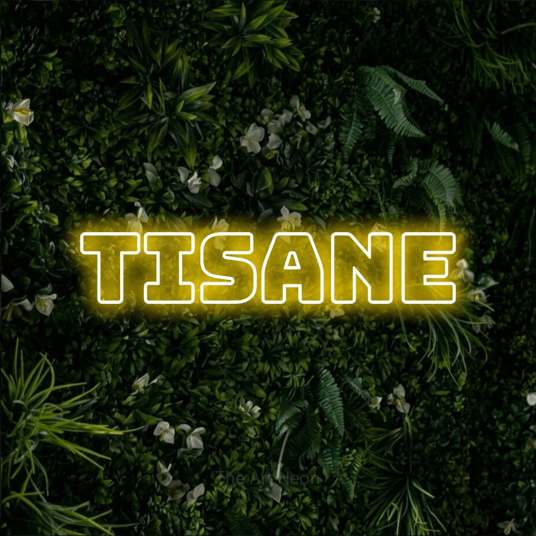 “Tisane” LED neon sign in yellow, with bold outline lettering, shown against a dense green plant wall.