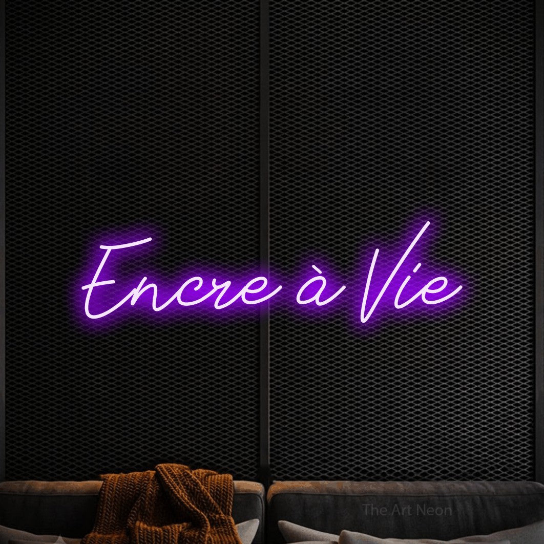 “Encre à vie” LED neon sign in purple, with cursive lettering, shown against a modern dark-toned seating area.