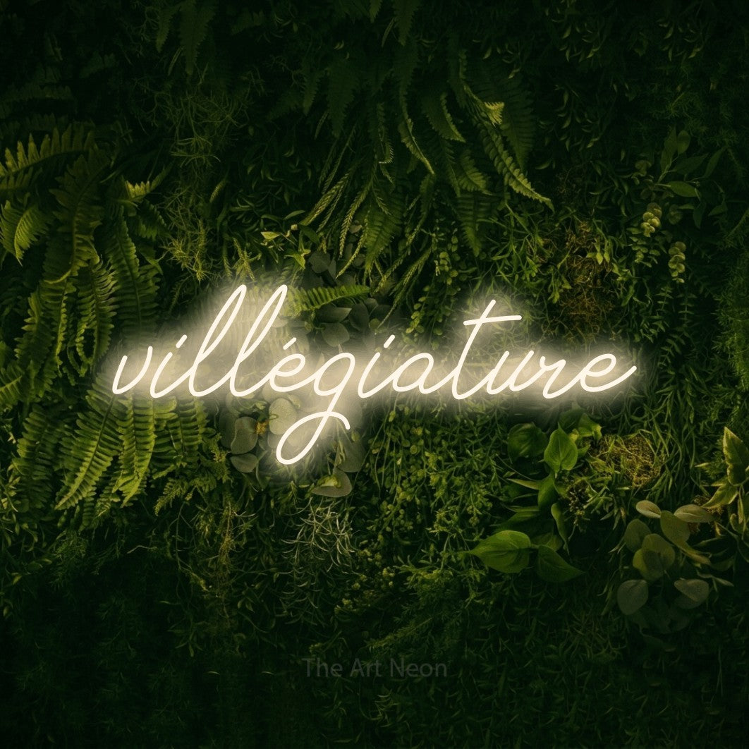Enseigne néon LED « Villégiature » en blanc chaud, en lettrage cursif, présentée sur un fond sombre de mousse et de forêt, pour un hôtel.