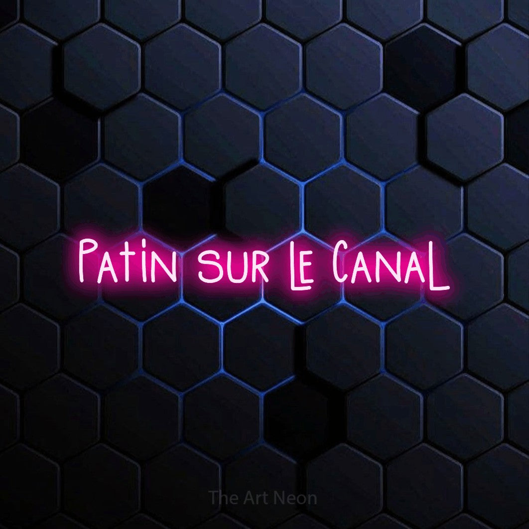 “Patin sur le canal” LED neon sign in hot pink, with narrow hand-drawn lettering, shown against a dark blue honeycomb pattern.