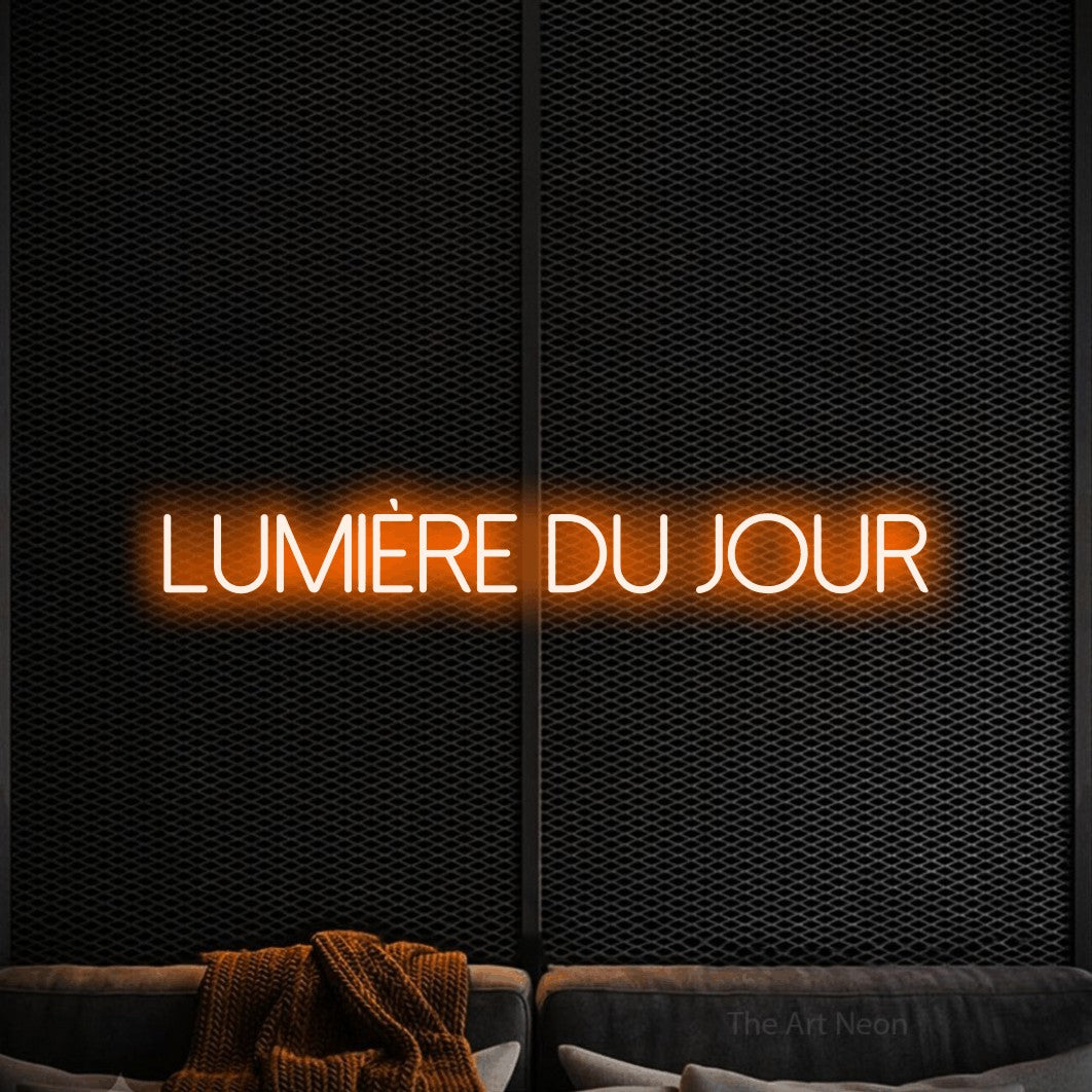 “Lumière du jour” LED neon sign in orange, with thin sans-serif lettering, shown against a modern dark-toned seating area.