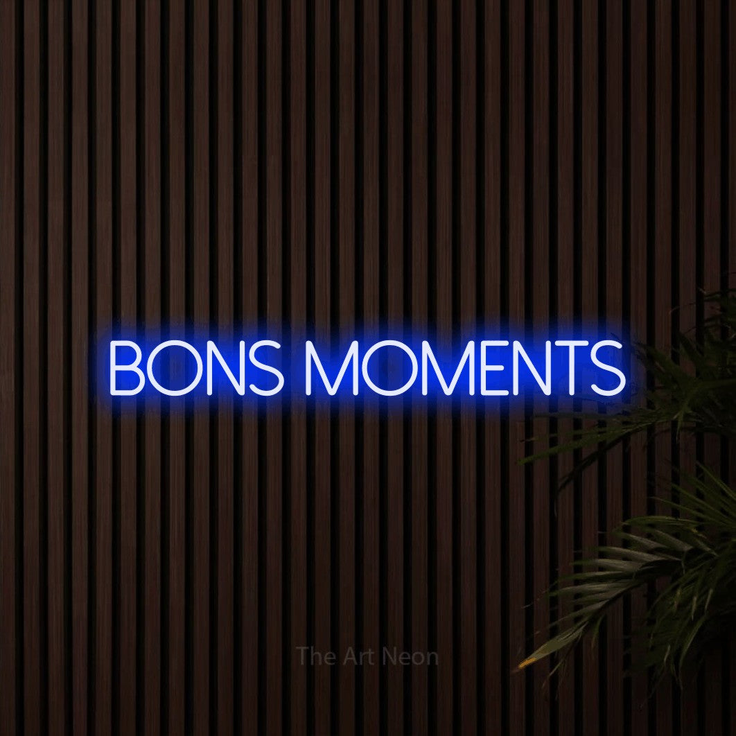 “Bons moments” LED neon sign in blue, with thin sans-serif lettering, shown against dark wooden wall slats.