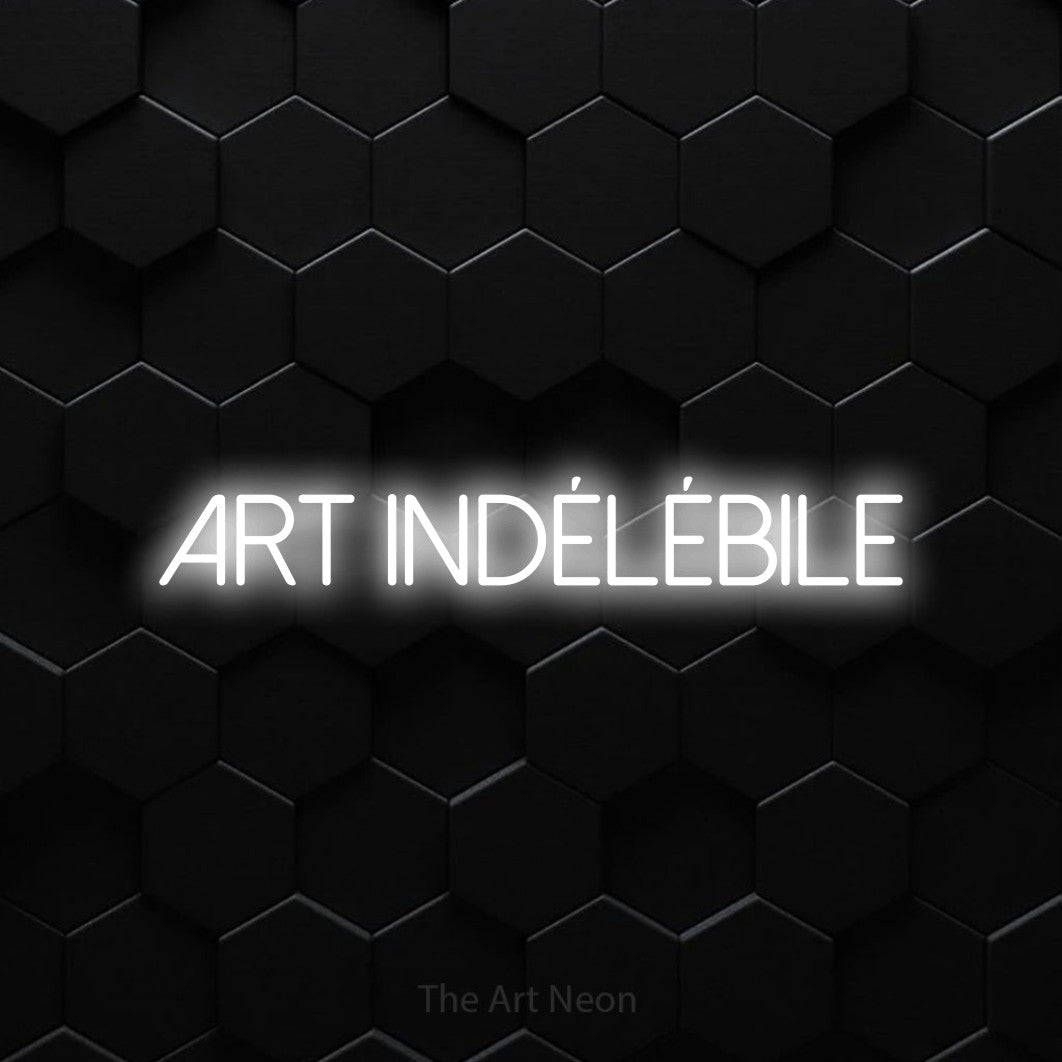 “Art indélébile” LED neon sign in cool white, with thin sans-serif lettering, shown against black hexagonal wall tiles.