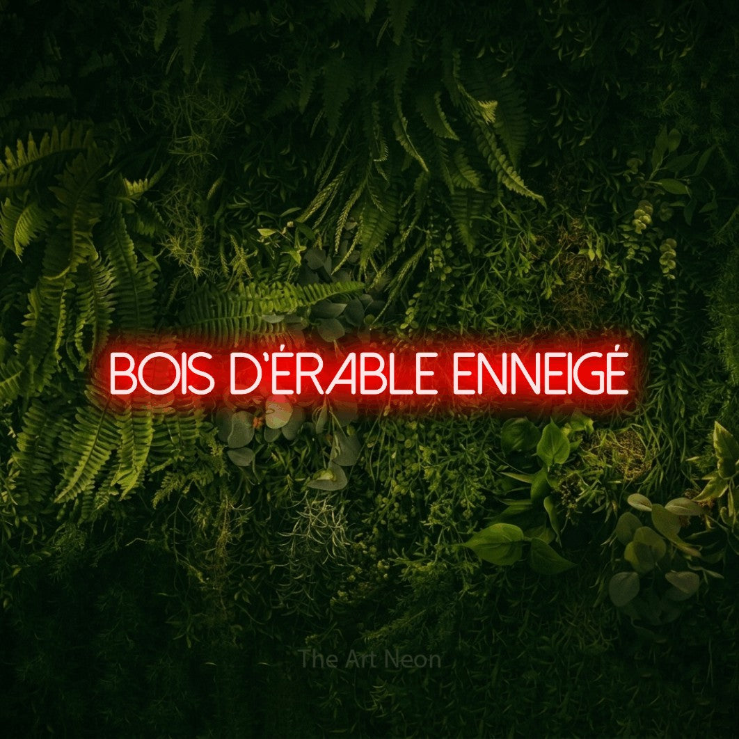 “Bois d'érable enneigé” LED neon sign in red, with thin sans-serif lettering, shown against a dark moss and forest backdrop.