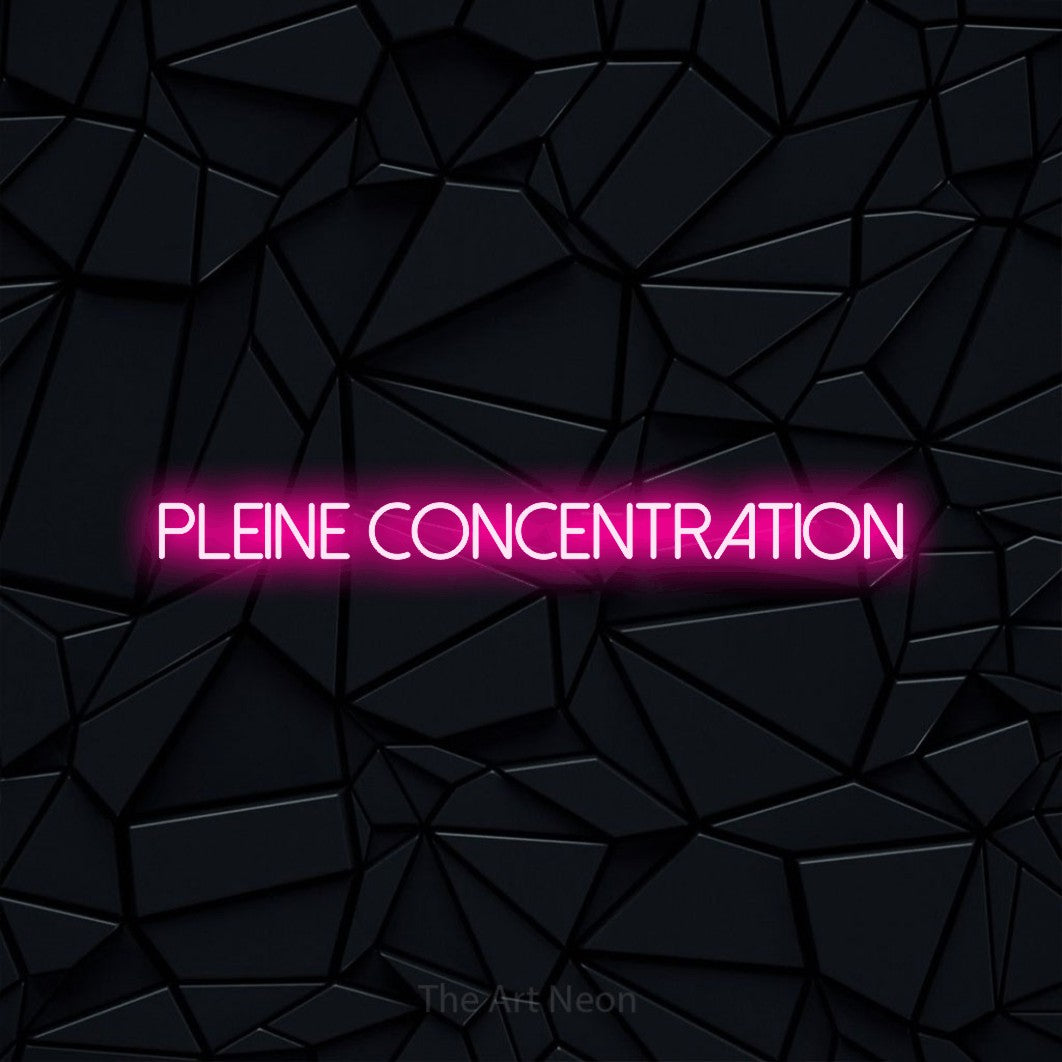 “Pleine concentration” LED neon sign in hot pink, with thin sans-serif lettering, shown against a black polygonal surface.
