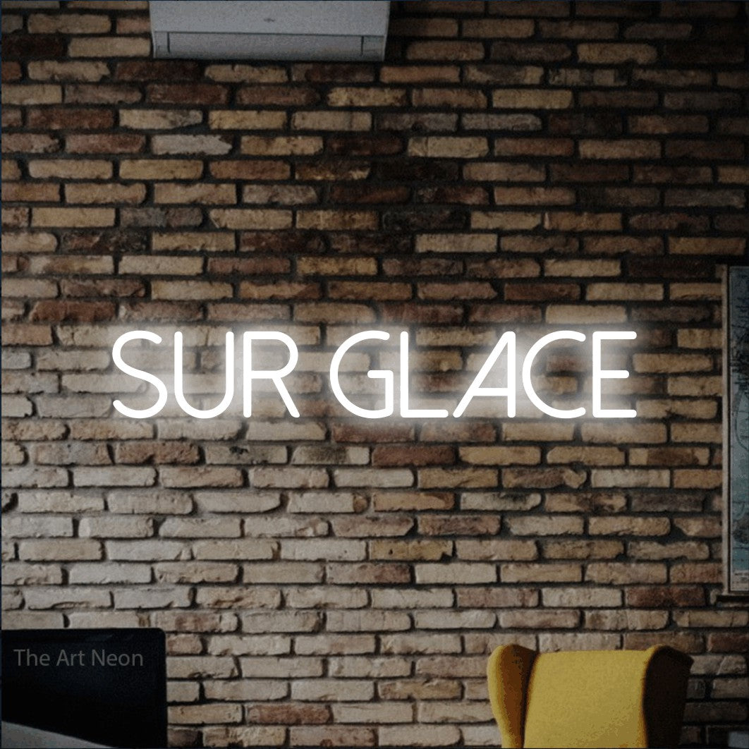 “Sur glace” LED neon sign in cool white, with thin sans-serif lettering, shown against warm-toned brickwork.