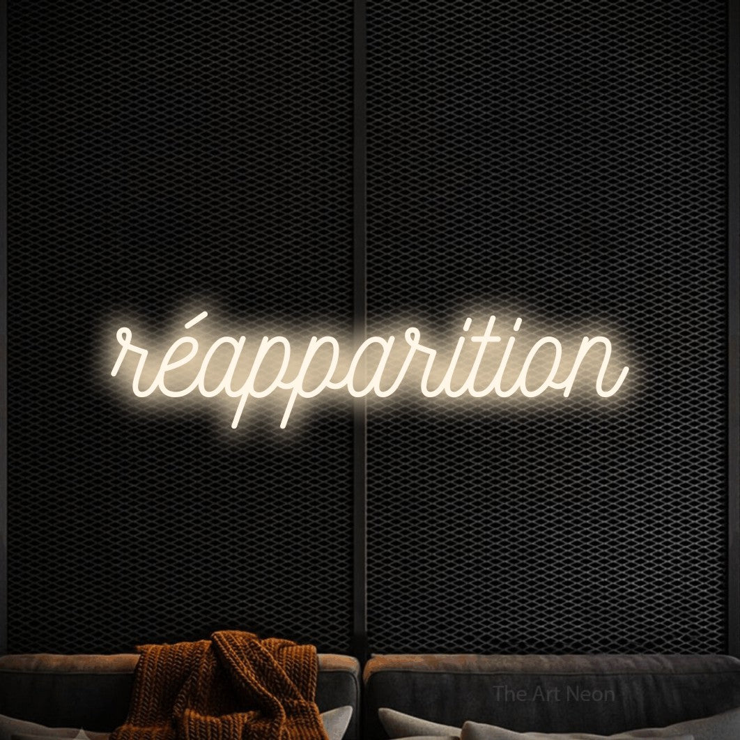 “Réapparition” LED neon sign in warm white, with ornate cursive lettering, shown against a modern dark-toned seating area.