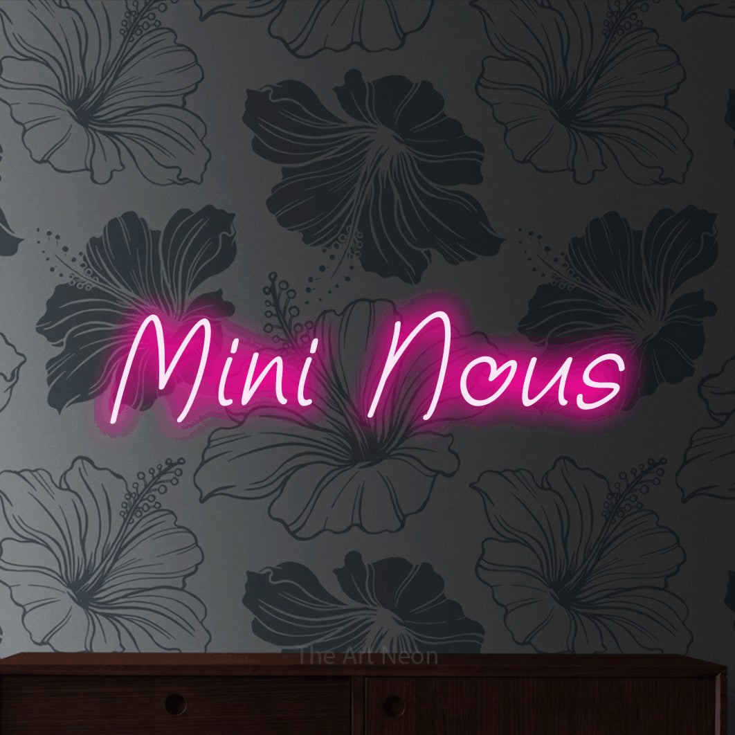 Enseigne néon LED « Mini nous » en rose vif, en écriture manuscrite inclinée, présentée sur un mur gris à motifs floraux, pour une fête prénatale.
