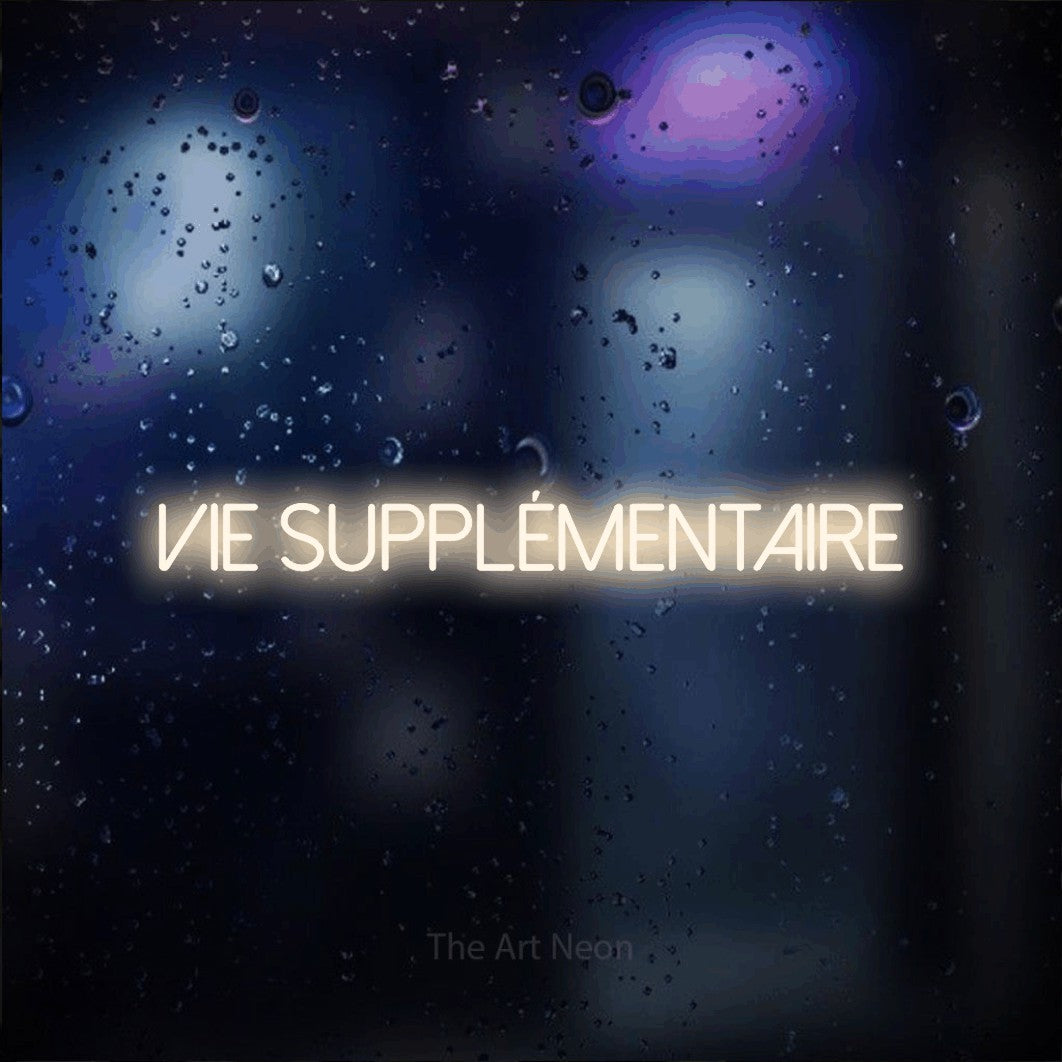 “Vie supplémentaire” LED neon sign in warm white, with thin sans-serif lettering, shown against glass with blue and purple reflections.