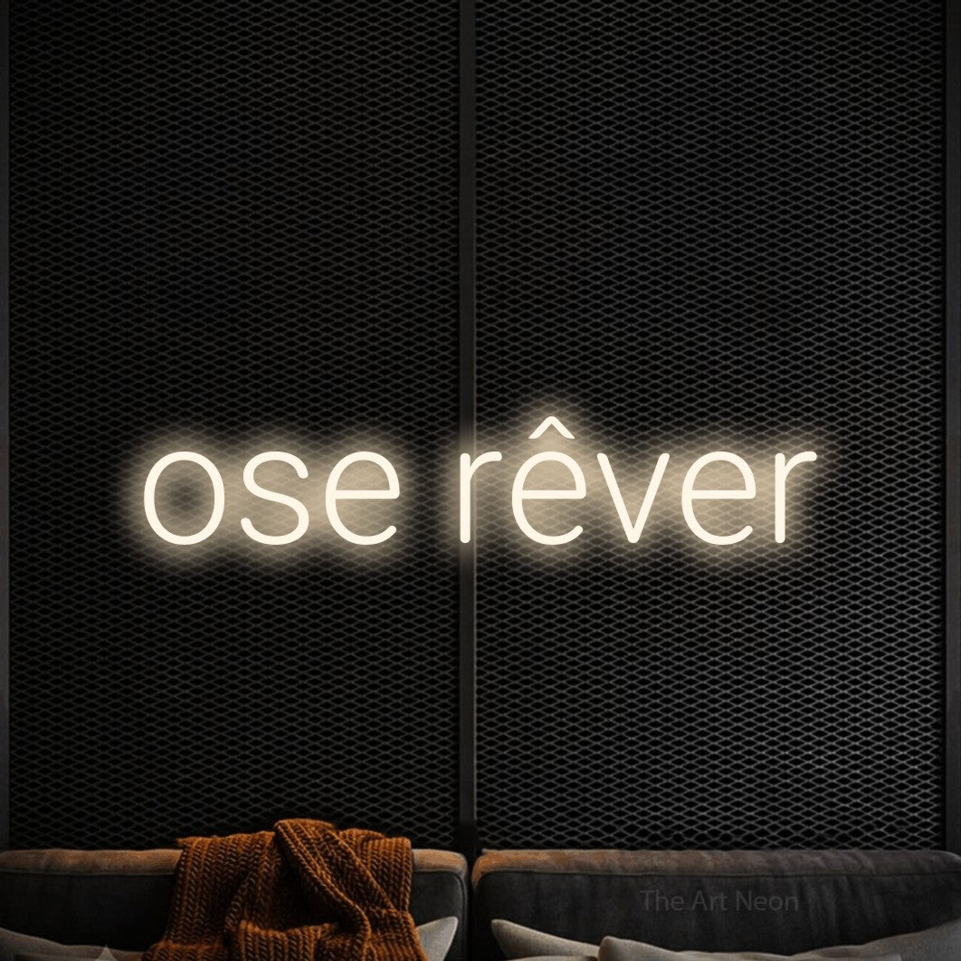 “Ose rêver” LED neon sign in warm white, with rounded sans-serif lettering, shown against a modern dark-toned seating area.