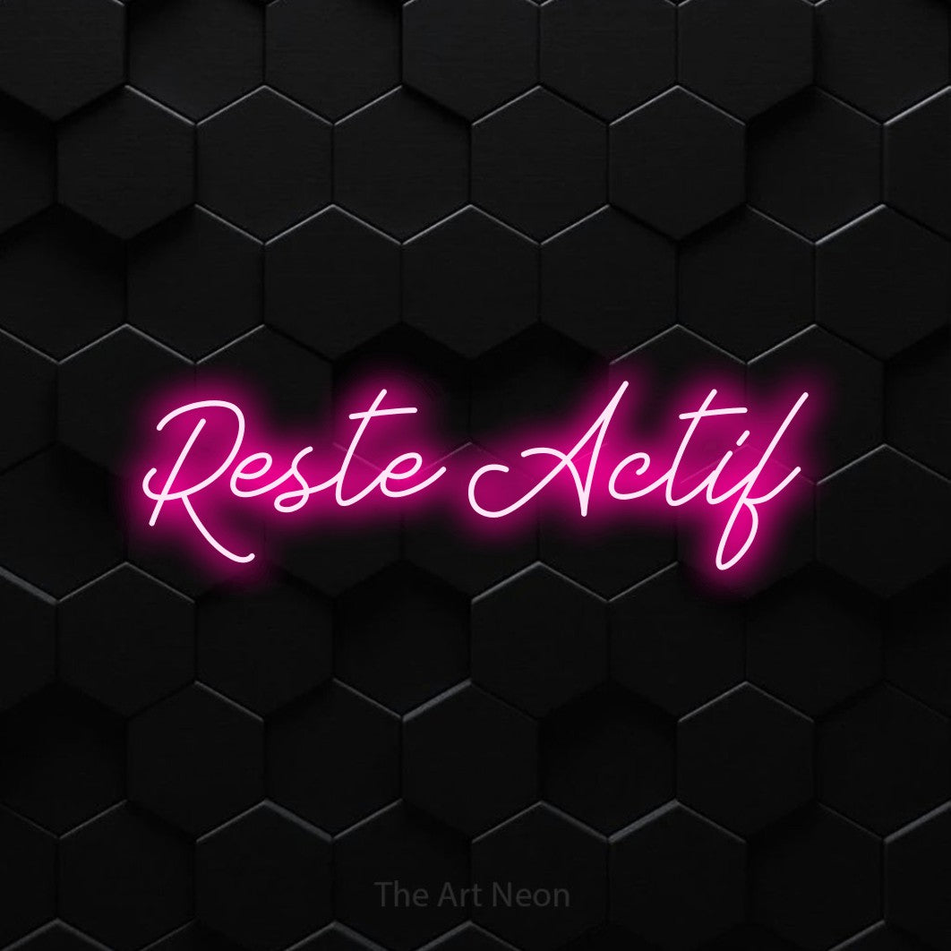 Décoration murale en néon LED « Reste actif » en rose vif, en lettrage cursif, installée sur un mur de carreaux hexagonaux noirs, pour un espace d’entraînement.