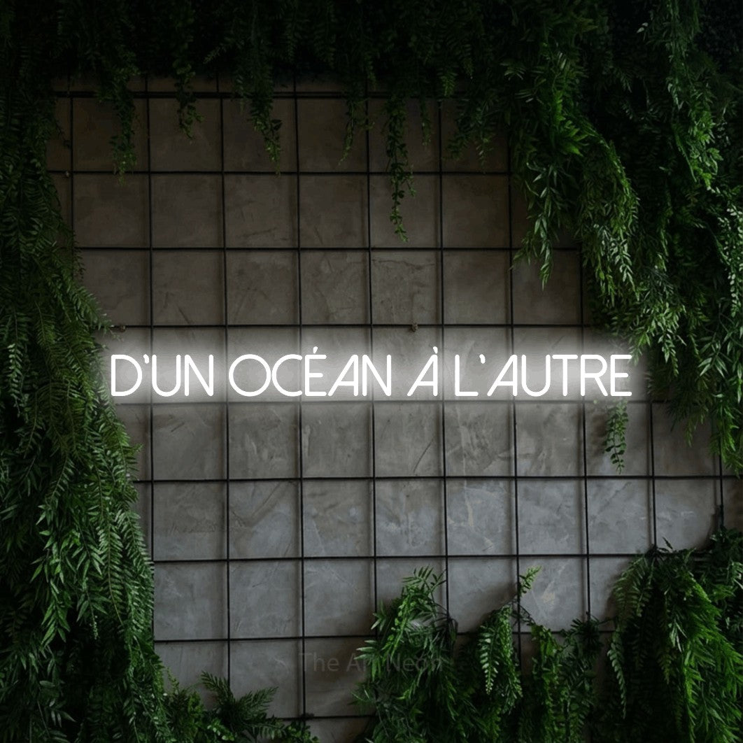 Aperçu d’une enseigne néon LED « D'un océan à l'autre » en blanc froid, en lettres fines sans empattement, photographiée sur une grille de béton couverte de lierre, pour un décor canadien.