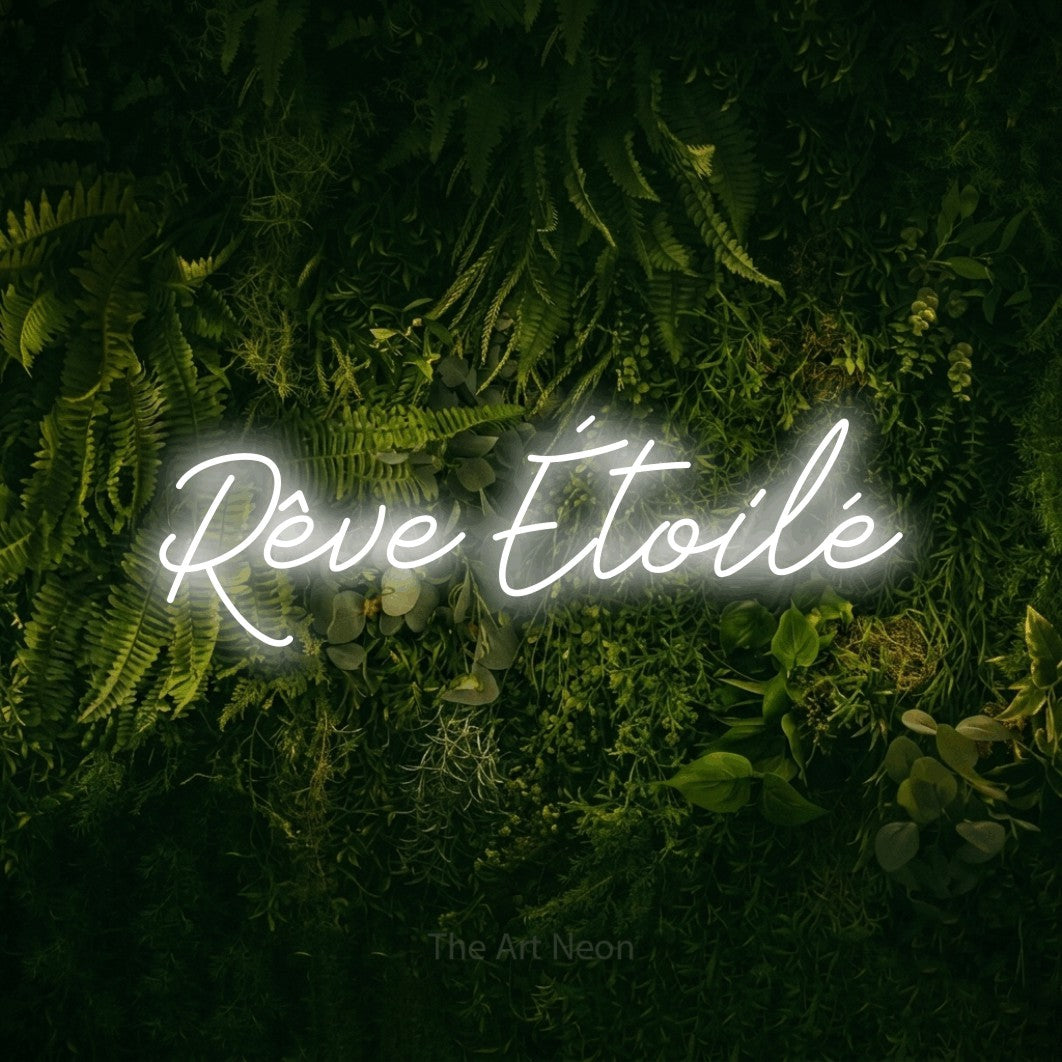 “Rêve étoilé” LED neon sign in cool white, with cursive lettering, shown against a dark moss and forest backdrop.