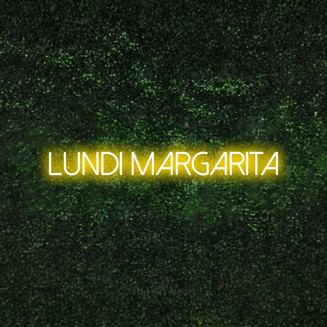 “Lundi margarita” LED neon sign in yellow, with thin sans-serif lettering, shown against a textured green hedge.