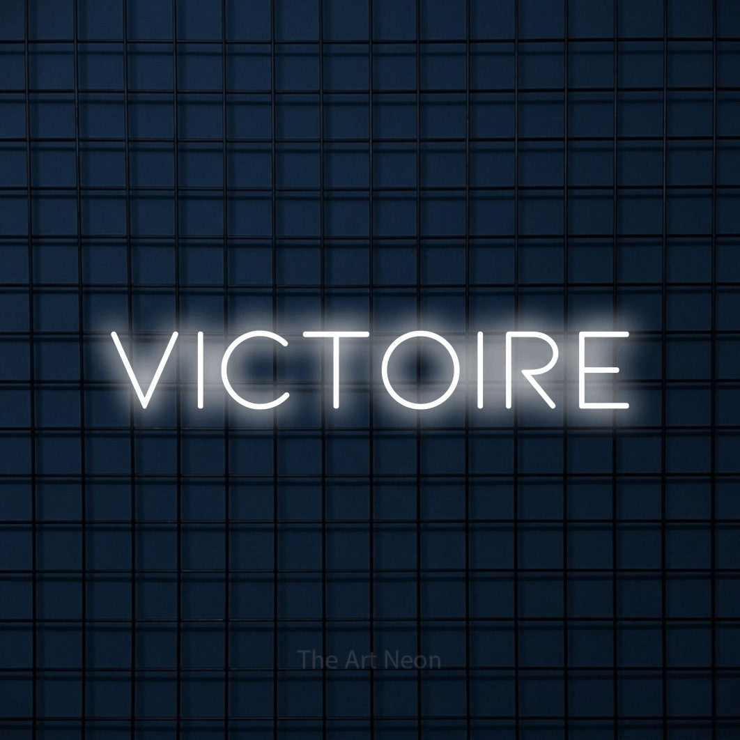 “Victoire” LED neon sign in cool white, with thin, widely spaced lettering, shown against a dark blue grid.