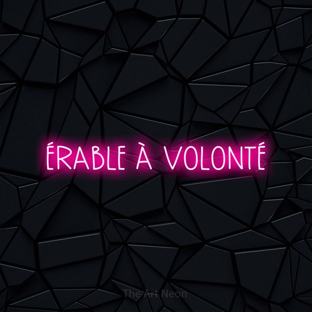 “Érable à volonté” LED neon sign in hot pink, with narrow hand-drawn lettering, shown against a black polygonal surface.