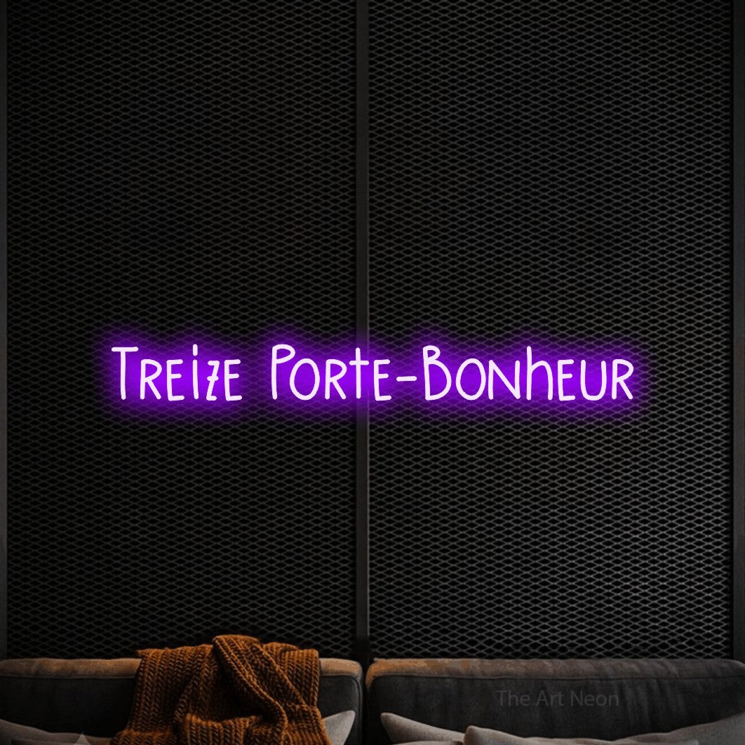 “Treize porte-bonheur” LED neon sign in purple, with narrow hand-drawn lettering, shown against a modern dark-toned seating area.