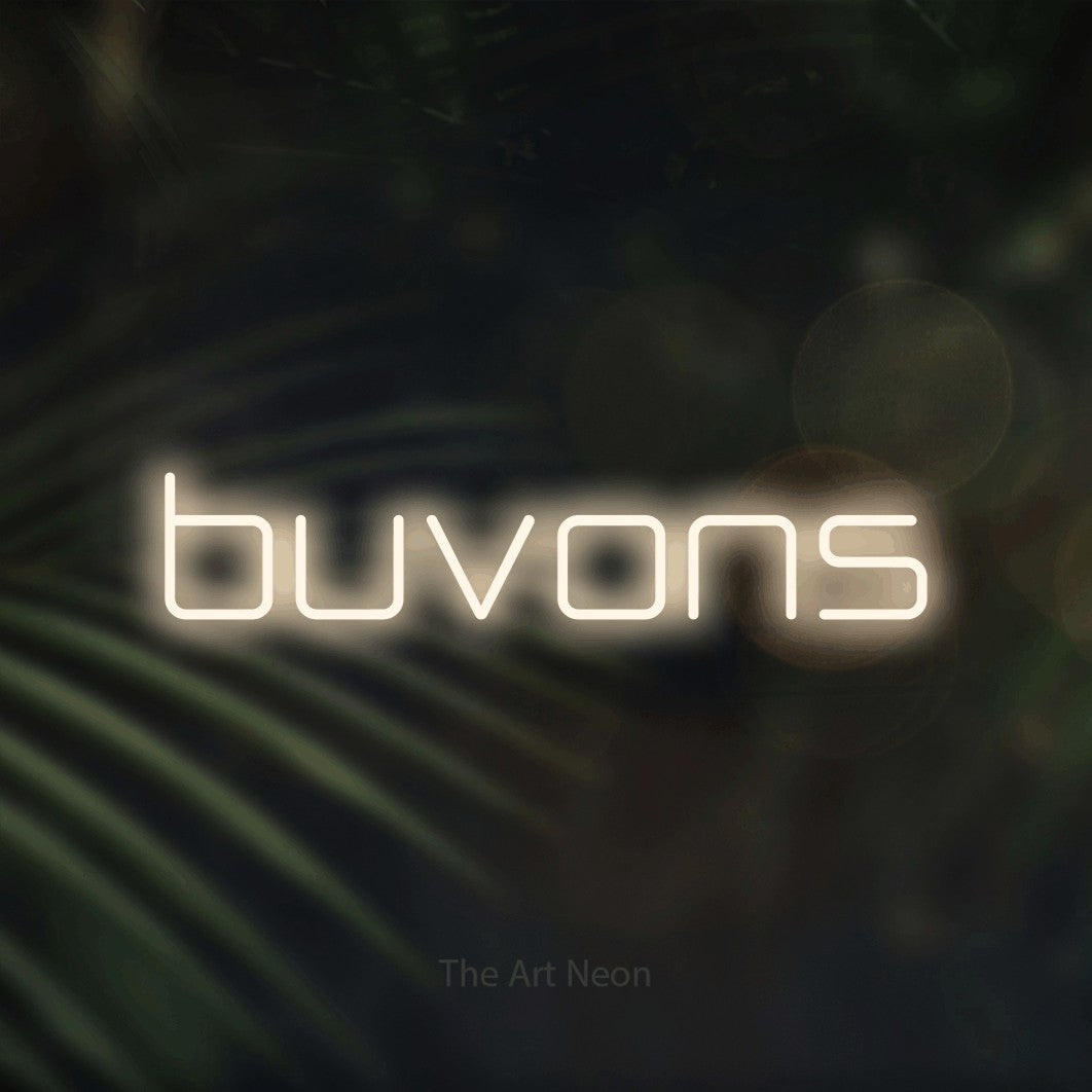 “Buvons” LED neon sign in warm white, with rounded geometric lettering, shown against a blurred palm and bokeh-light backdrop.