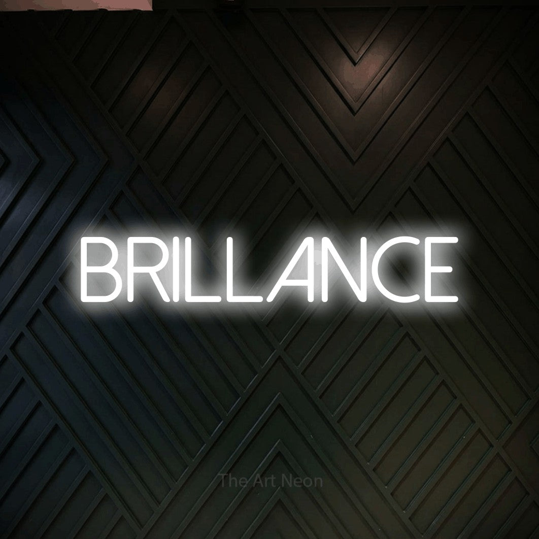 “Brillance” LED neon sign in cool white, with thin sans-serif lettering, shown against a black chevron-patterned wood wall.