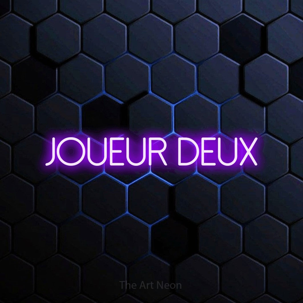 “Joueur deux” LED neon sign in purple, with thin sans-serif lettering, shown against a dark blue honeycomb pattern.