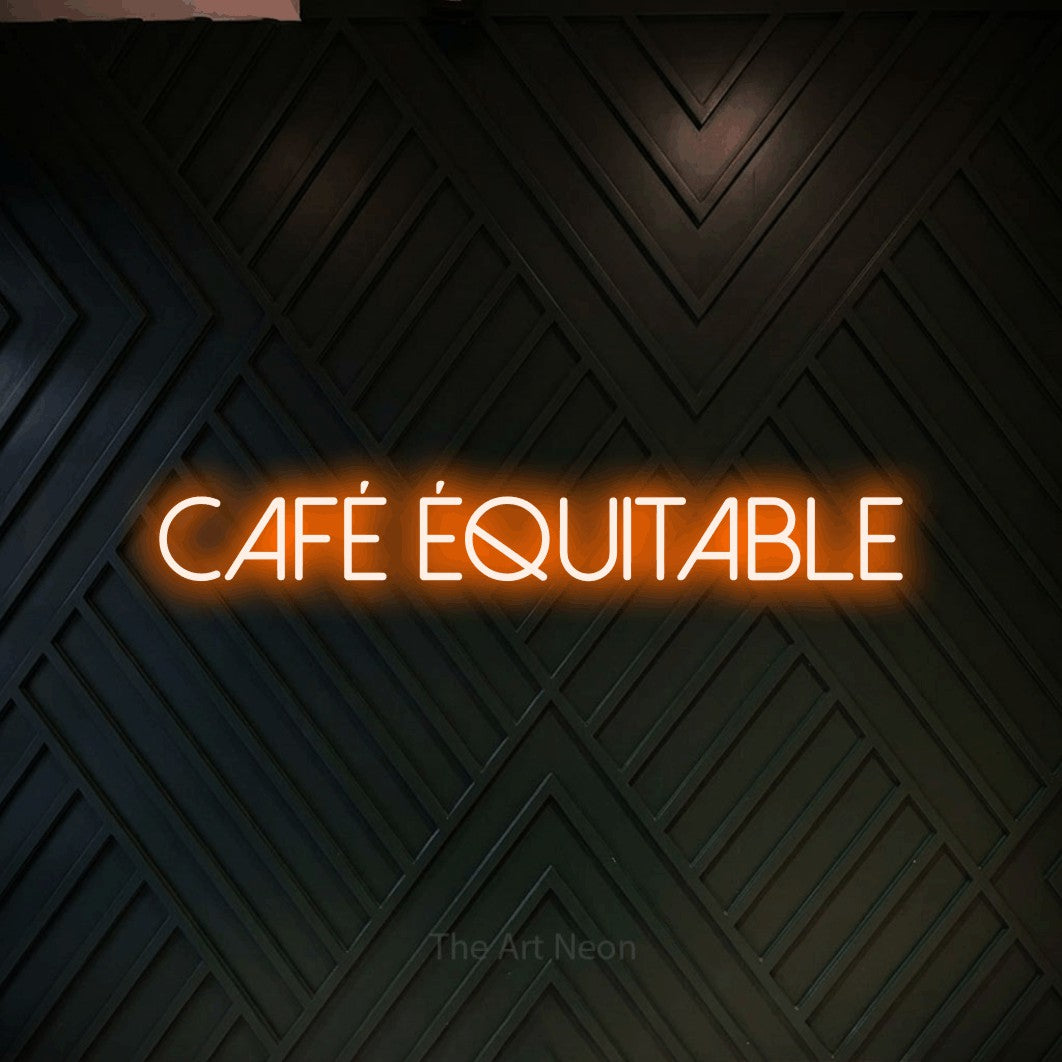 “Café équitable” LED neon sign in orange, with thin sans-serif lettering, shown against a black chevron-patterned wood wall.