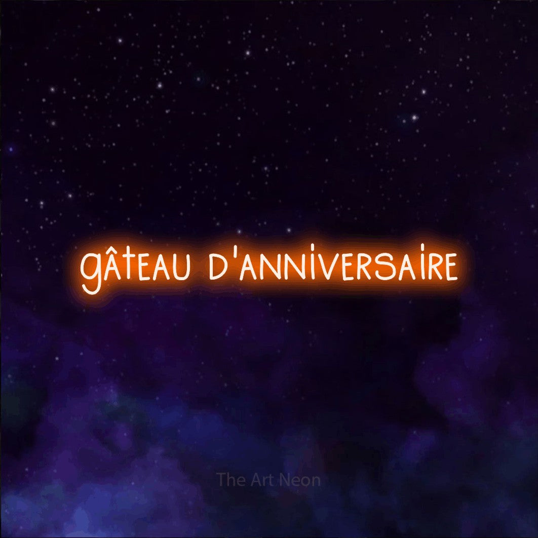 “Gâteau d'anniversaire” LED neon sign in orange, with narrow hand-drawn lettering, shown against a purple galaxy backdrop.