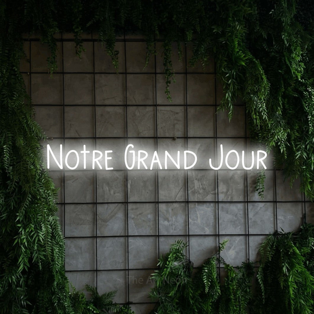 “Notre grand jour” LED neon sign in cool white, with narrow hand-drawn lettering, shown against an ivy-covered concrete grid.