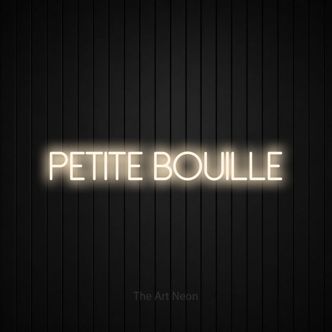 “Petite bouille” LED neon sign in warm white, with thin sans-serif lettering, shown against black vertical wall slats.