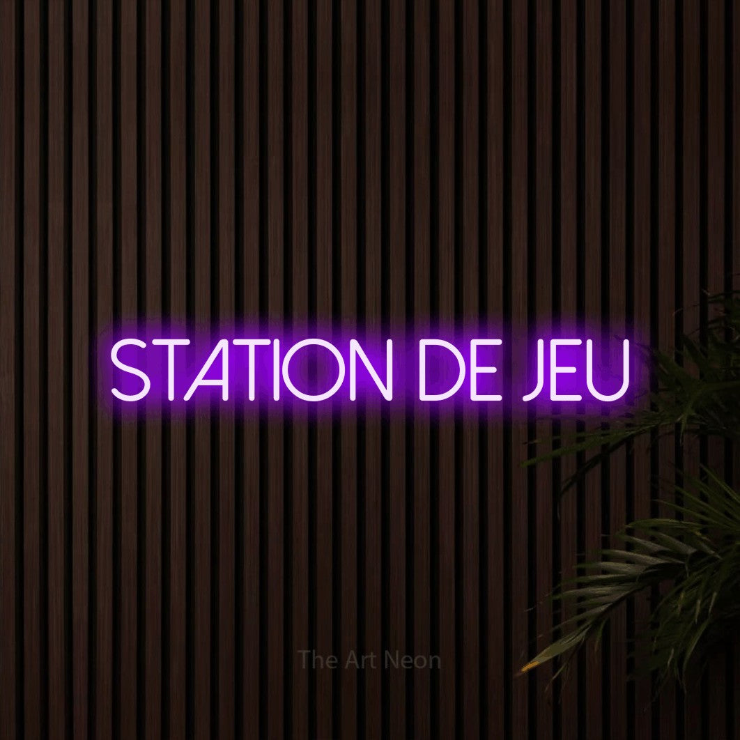 “Station de jeu” LED neon sign in purple, with thin sans-serif lettering, shown against dark wooden wall slats.