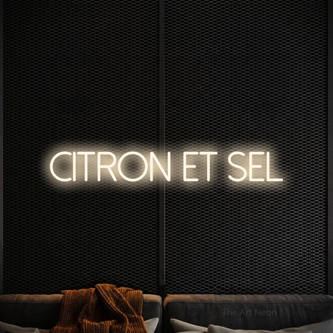 “Citron et sel” LED neon sign in warm white, with thin sans-serif lettering, shown against a modern dark-toned seating area.