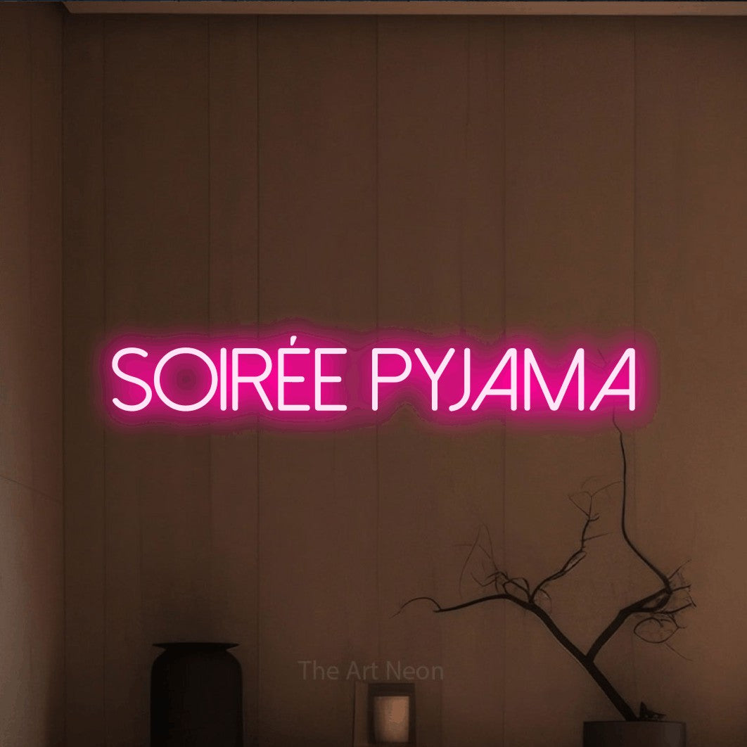 “Soirée pyjama” LED neon sign in hot pink, with thin sans-serif lettering, shown against a simple earth-toned interior.