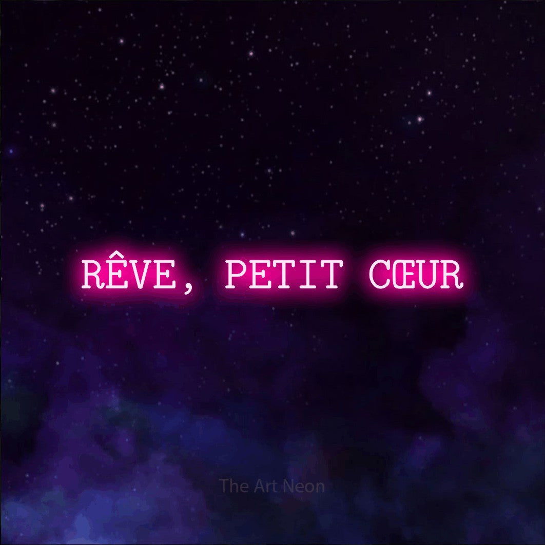 Décoration murale en néon LED « Rêve, petit cœur » en rose vif, en caractères de machine à écrire, installée sur une texture de galaxie violette, pour une chambre d’enfant.