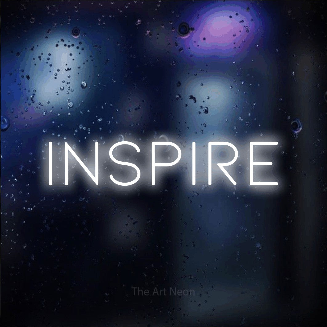 “Inspire” LED neon sign in cool white, with thin, widely spaced lettering, shown against glass with blue and purple reflections.