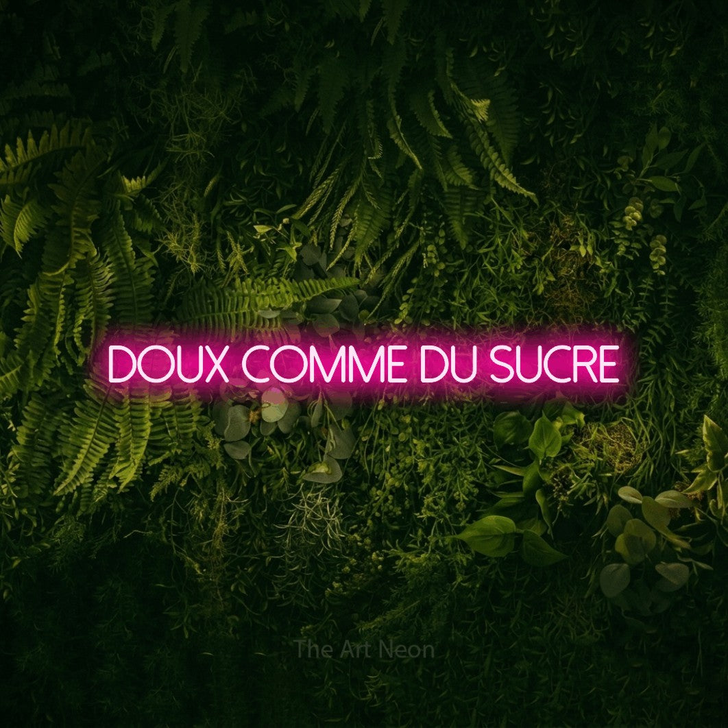 Lettrage en néon LED « Doux comme du sucre » en rose vif, en lettres fines sans empattement, présenté sur un fond sombre de mousse et de forêt, pour une fête prénatale.