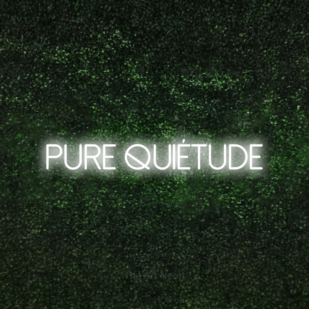 “Pure quiétude” LED neon sign in cool white, with thin sans-serif lettering, shown against a textured green hedge.