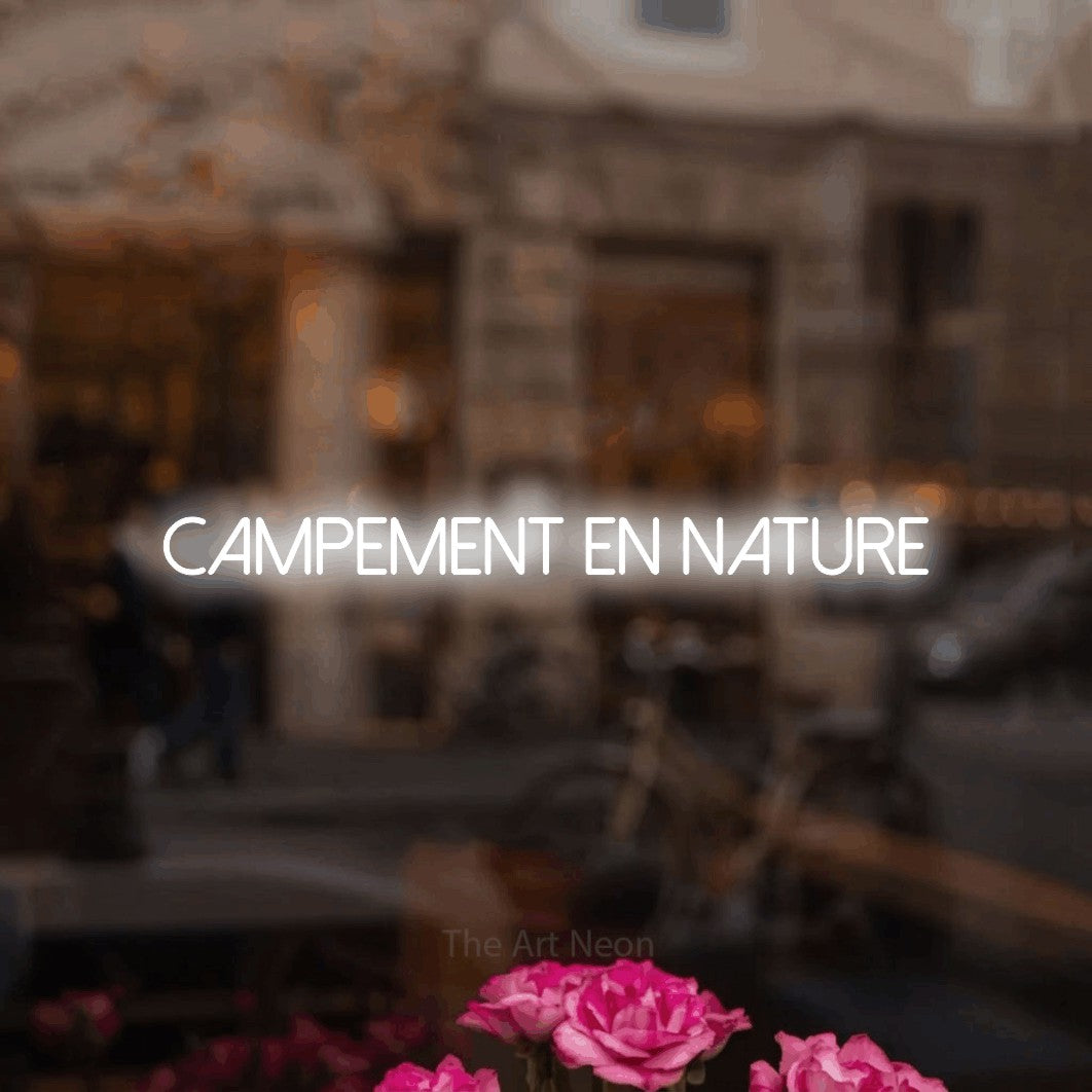 “Campement en nature” LED neon sign in cool white, with thin sans-serif lettering, shown against a blurred café-bar interior.
