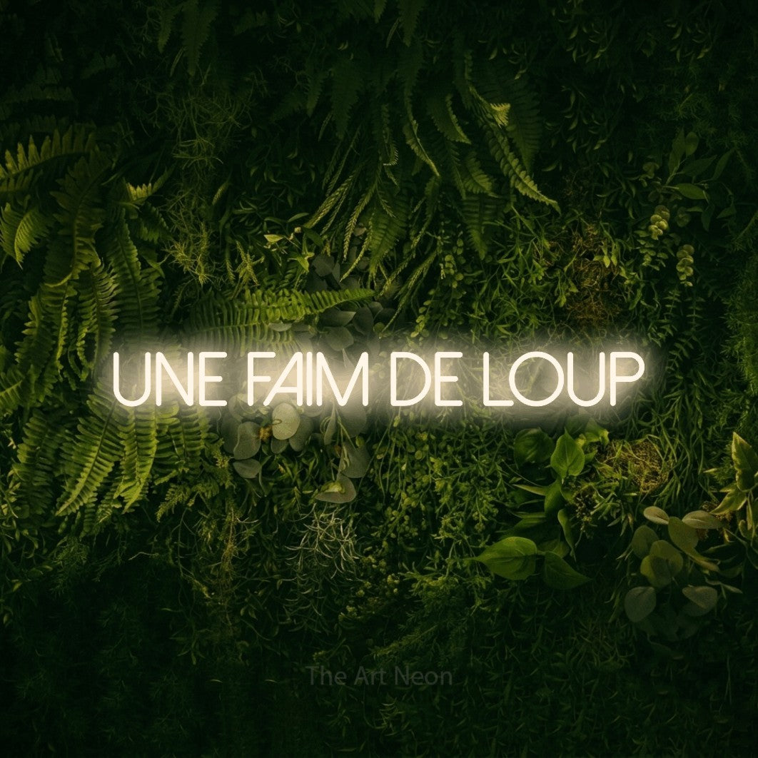 Enseigne néon LED « Une faim de loup » en blanc chaud, en lettres fines sans empattement, présentée sur un fond sombre de mousse et de forêt, pour un restaurant.
