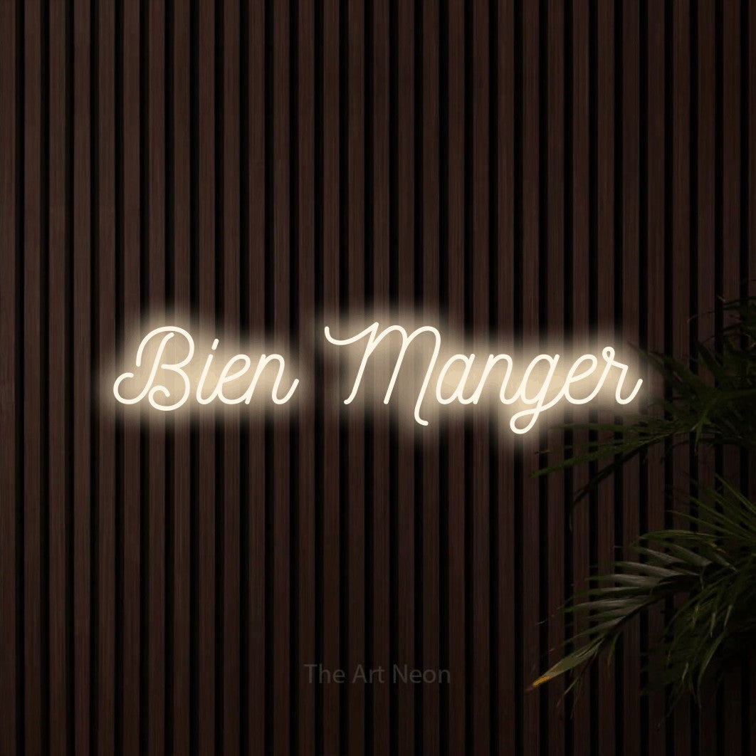 “Bien manger” LED neon sign in warm white, with ornate cursive lettering, shown against dark wooden wall slats.