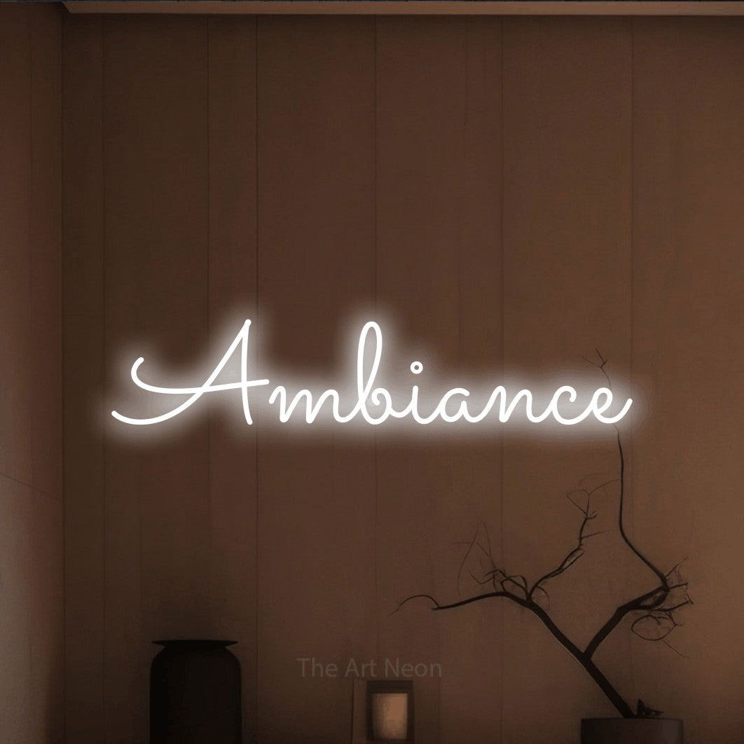 “Ambiance” LED neon sign in cool white, with looped cursive lettering, shown against a simple earth-toned interior.