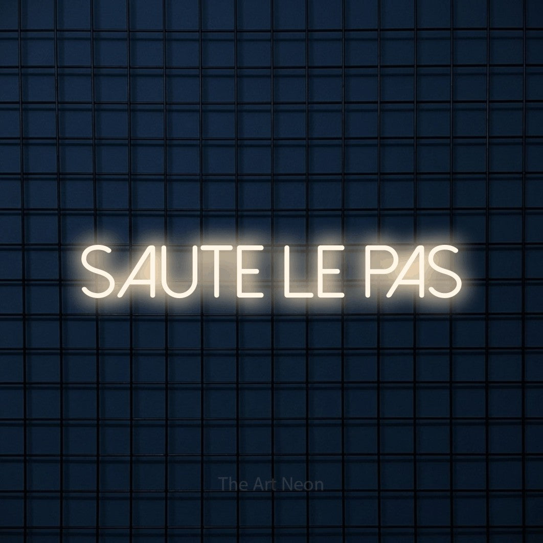 “Saute le pas” LED neon sign in warm white, with thin sans-serif lettering, shown against a dark blue grid.