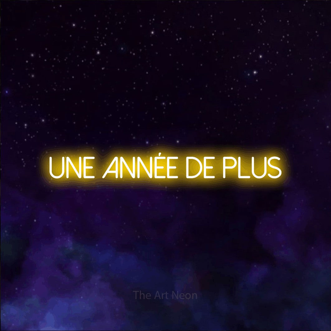 “Une année de plus” LED neon sign in yellow, with thin sans-serif lettering, shown against a purple galaxy backdrop.