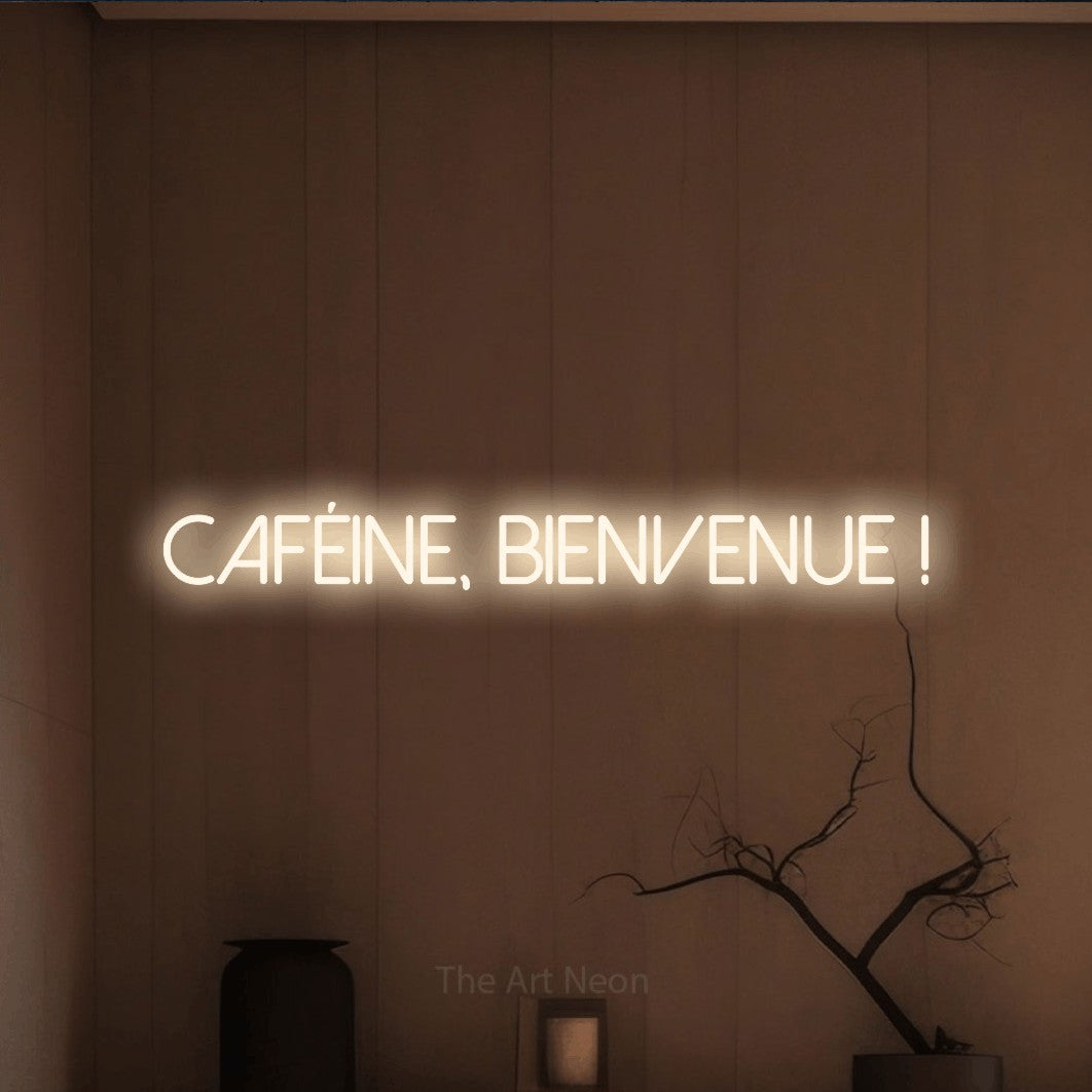 “Caféine, bienvenue !” LED neon sign in warm white, with thin sans-serif lettering, shown against a simple earth-toned interior.